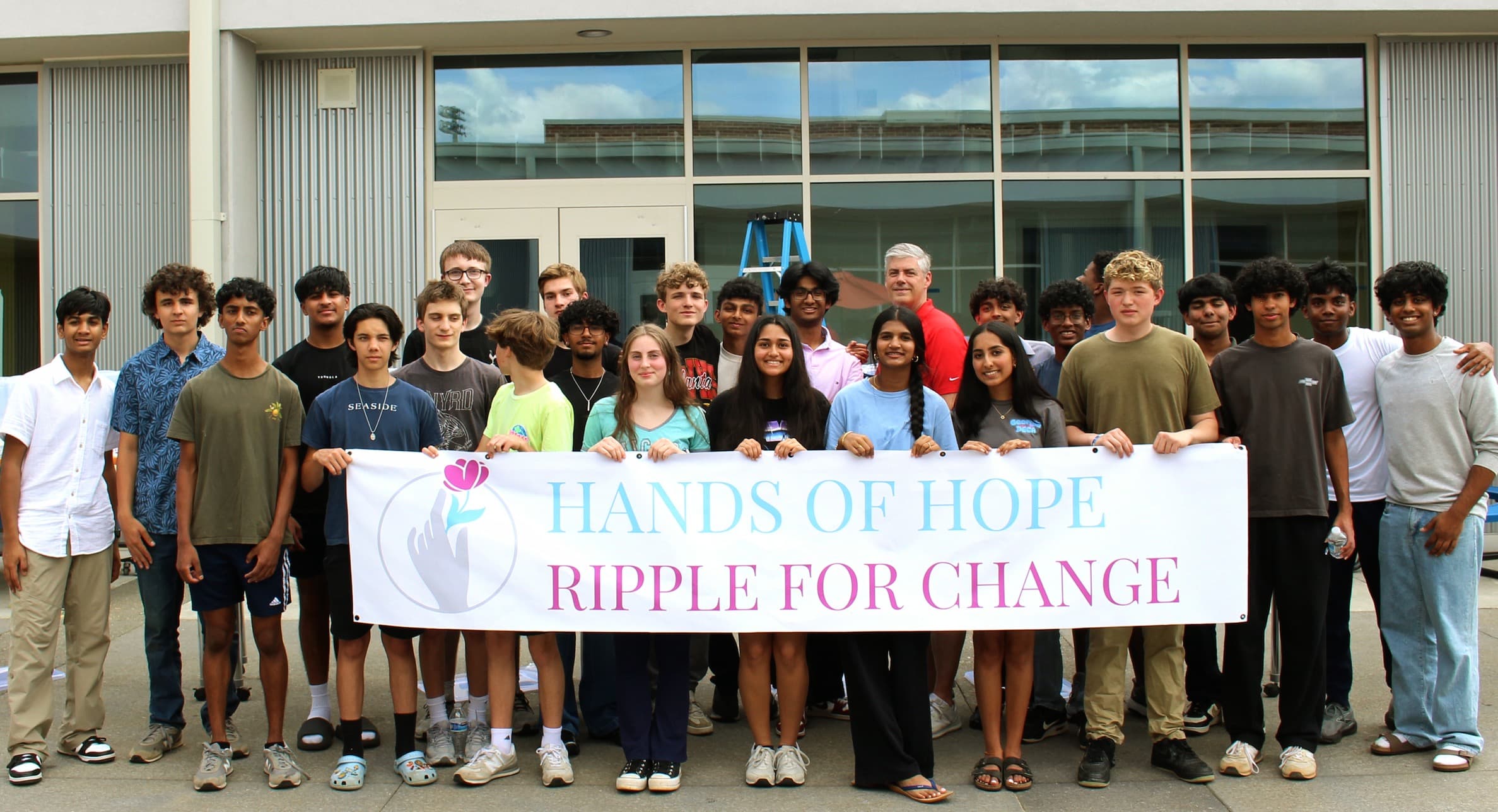 Hands of Hope students gathered behind the Ripple for Change banner